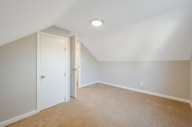bonus room featuring lofted ceiling, light colored carpet, and baseboards