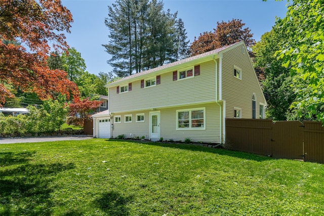 colonial house featuring an attached garage, asphalt driveway, and a gate