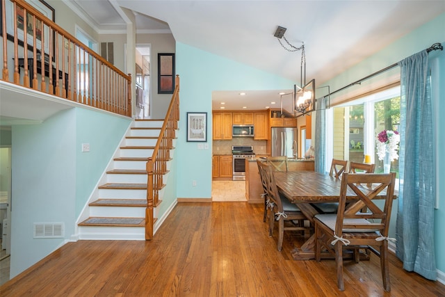 dining space featuring wood finished floors, stairway, a chandelier, baseboards, and high vaulted ceiling
