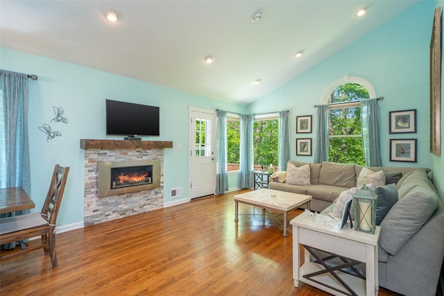 living room with wood finished floors, a stone fireplace, recessed lighting, high vaulted ceiling, and baseboards
