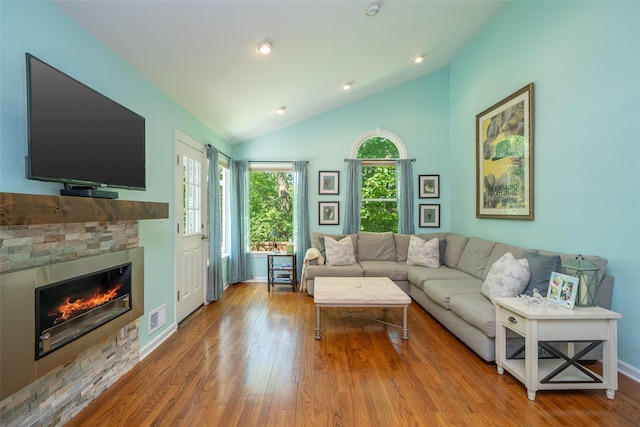 living area featuring wood finished floors, lofted ceiling, a fireplace, baseboards, and recessed lighting