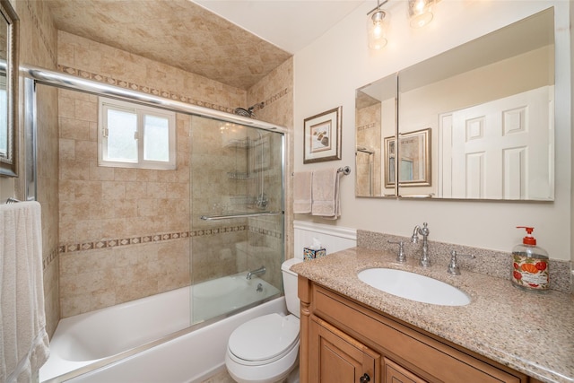 bathroom with combined bath / shower with glass door, vanity, and toilet
