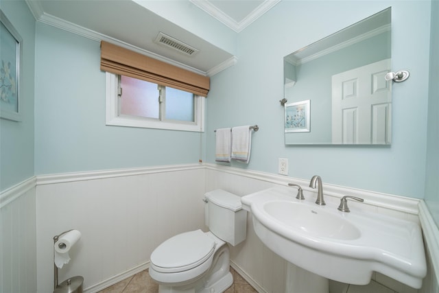 half bath with toilet, a wainscoted wall, crown molding, and a sink