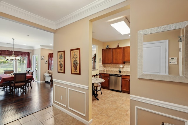 kitchen with tasteful backsplash, brown cabinetry, dishwasher, light tile patterned flooring, and crown molding