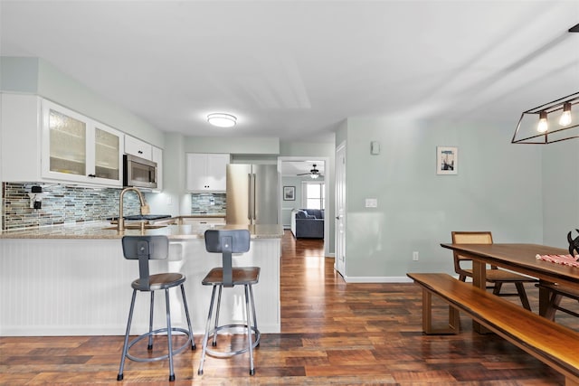 110 Gedney St, Nyack, NY 10960 - kitchen featuring appliances with stainless steel finishes, a peninsula, decorative backsplash, glass insert cabinets, and white cabinetry