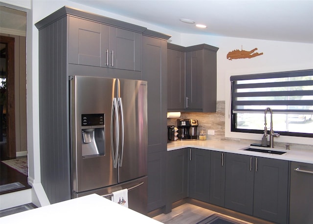 kitchen featuring tasteful backsplash, a sink, stainless steel fridge with ice dispenser, light countertops, and recessed lighting