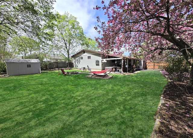 view of yard featuring an outdoor structure, a fenced backyard, and an outdoor fire pit