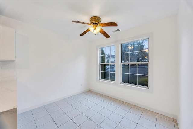 spare room featuring baseboards, visible vents, ceiling fan, and light tile patterned flooring