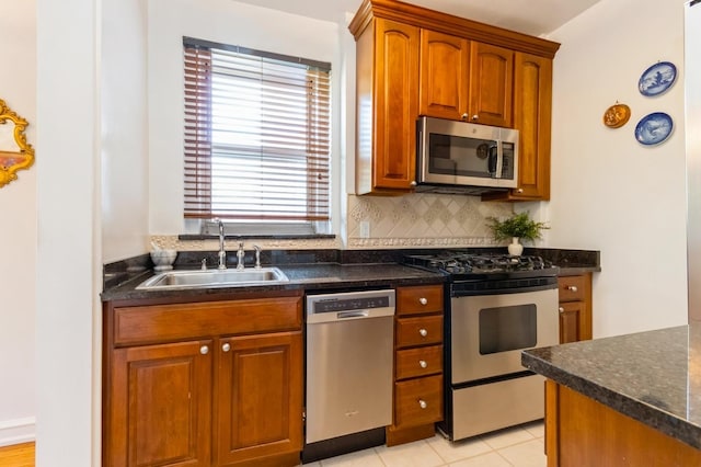 kitchen featuring a sink, backsplash, stainless steel appliances, and brown cabinetry