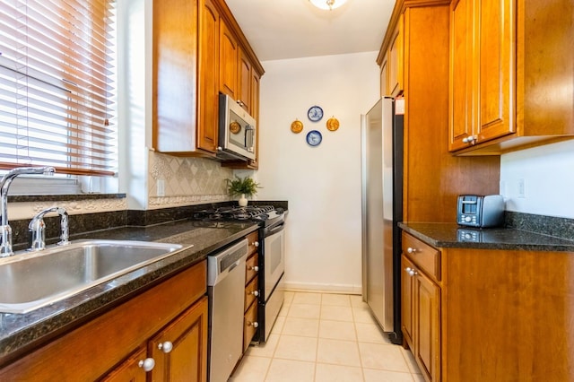 kitchen featuring a sink, light tile patterned floors, brown cabinets, and stainless steel appliances