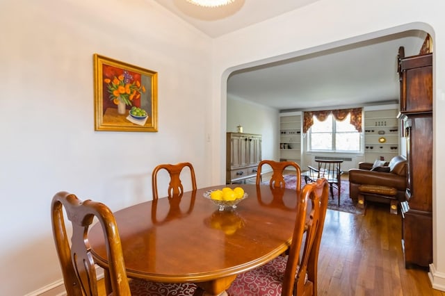 dining space with arched walkways and wood finished floors