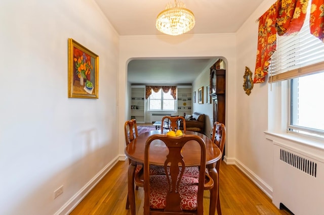 dining room with radiator heating unit, arched walkways, wood finished floors, and a chandelier