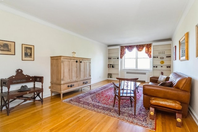 living area featuring light wood-style floors, ornamental molding, baseboards, and radiator heating unit