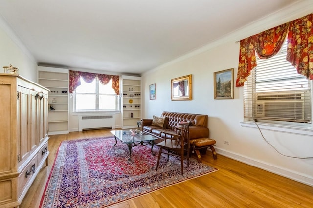 living area featuring crown molding, baseboards, radiator heating unit, and wood finished floors