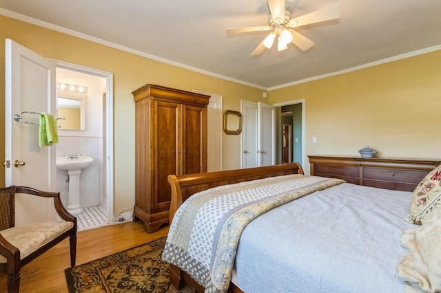 bedroom featuring crown molding, ceiling fan, ensuite bath, and wood finished floors
