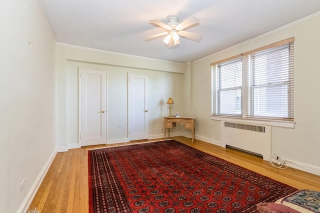 bedroom with ornamental molding, baseboards, radiator heating unit, a ceiling fan, and light wood-style flooring