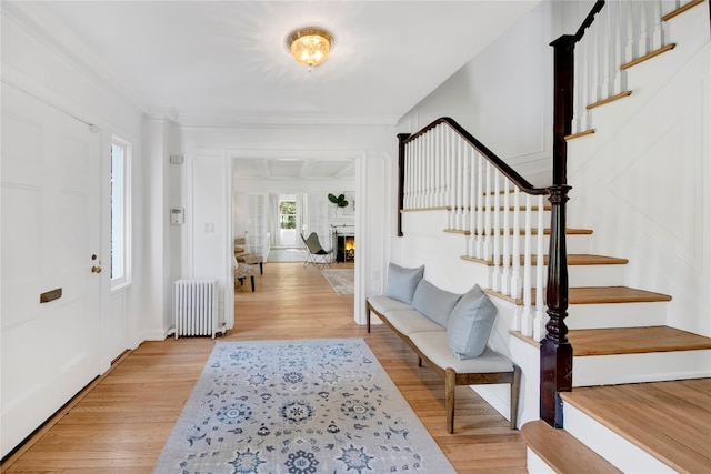 entrance foyer with radiator heating unit, stairway, and light wood-type flooring