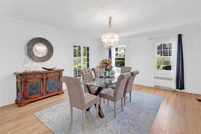 dining space with ornamental molding, radiator, a notable chandelier, and light wood-style flooring