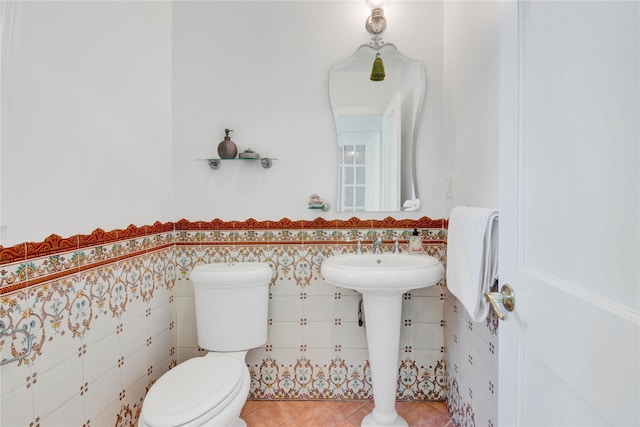 bathroom with a wainscoted wall, tile patterned flooring, toilet, and tile walls