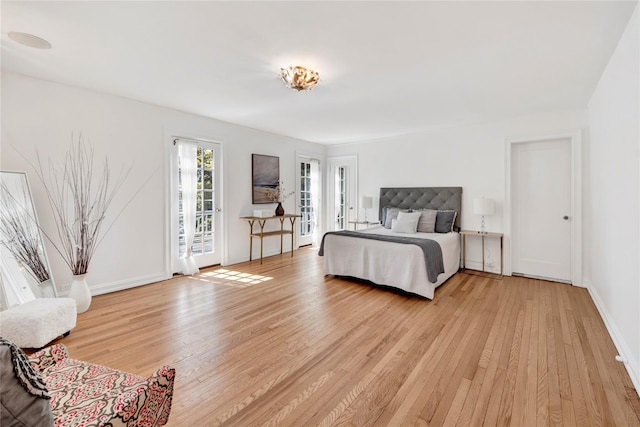 bedroom featuring baseboards, access to exterior, and light wood finished floors