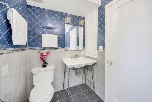 bathroom featuring tile patterned floors, toilet, and tile walls