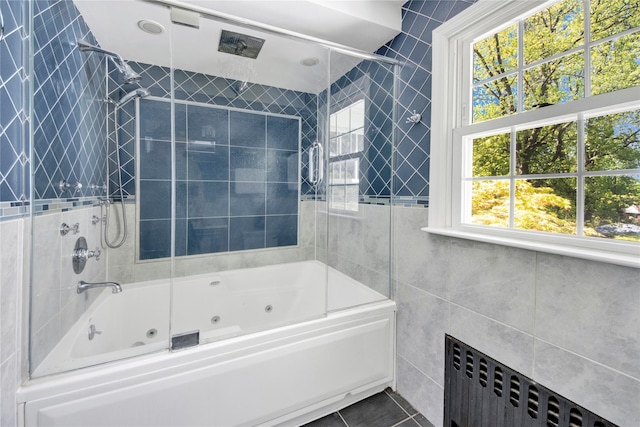 full bathroom featuring radiator heating unit, tile walls, and a combined bath / shower with jetted tub