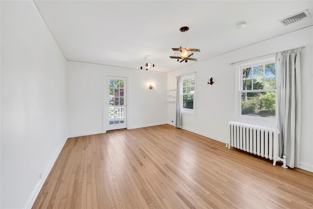 spare room with light wood-style floors, radiator, baseboards, and visible vents