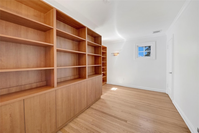 spare room featuring baseboards, ornamental molding, light wood-type flooring, and visible vents