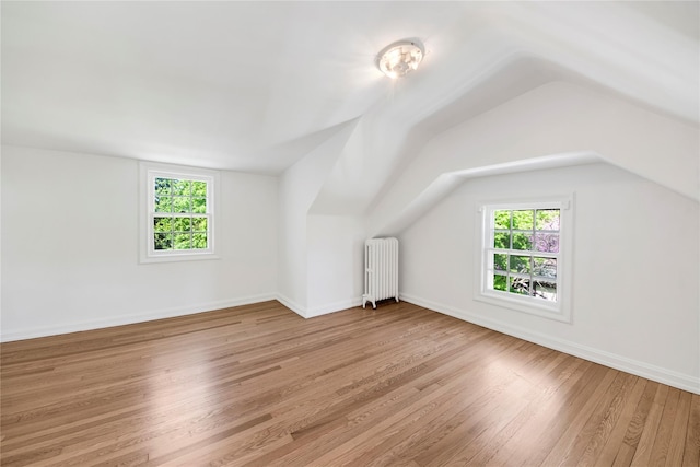 bonus room featuring plenty of natural light, radiator heating unit, vaulted ceiling, and wood finished floors