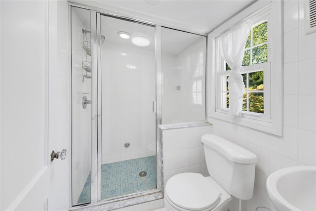 bathroom with tile walls, a stall shower, and toilet