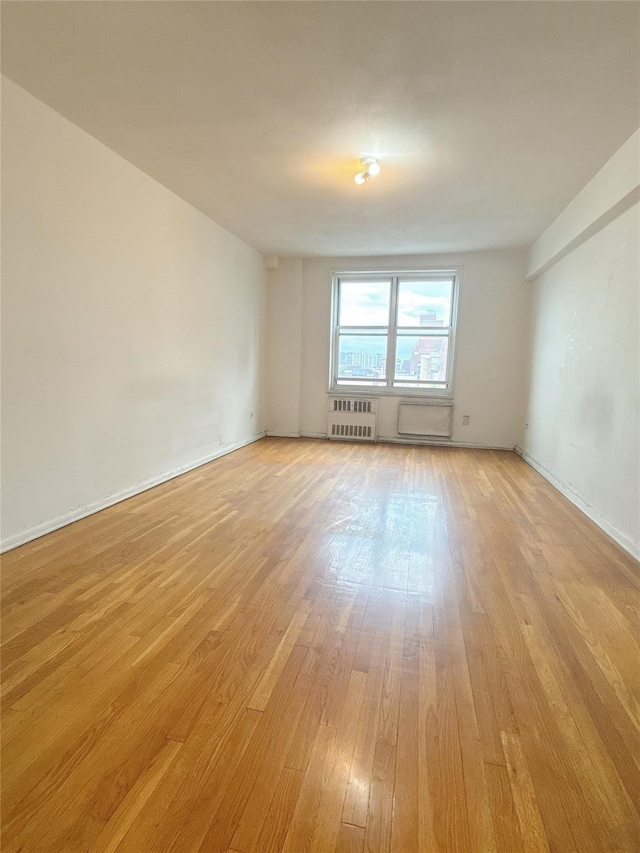 spare room featuring light wood finished floors and radiator