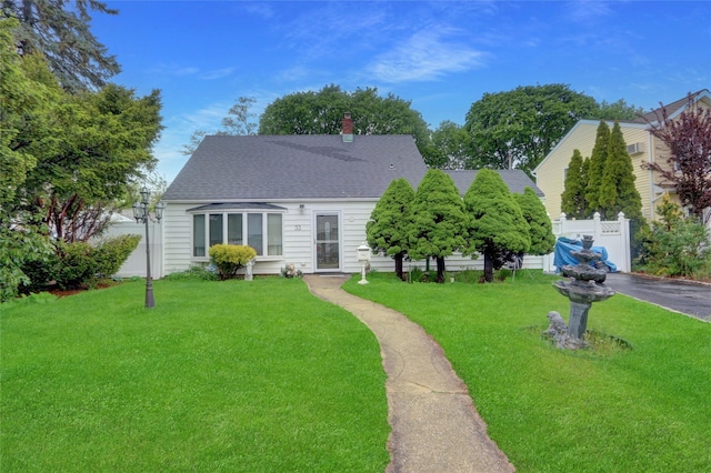 view of front of home featuring a shingled roof, a chimney, and asphalt driveway