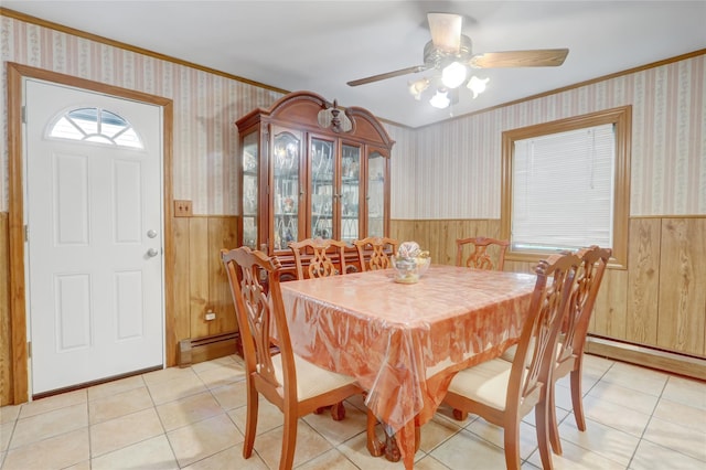 dining room featuring a wainscoted wall, wood walls, ornamental molding, ceiling fan, and light tile patterned floors