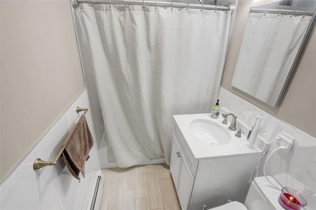 bathroom featuring a baseboard heating unit, vanity, and shower / tub combo with curtain