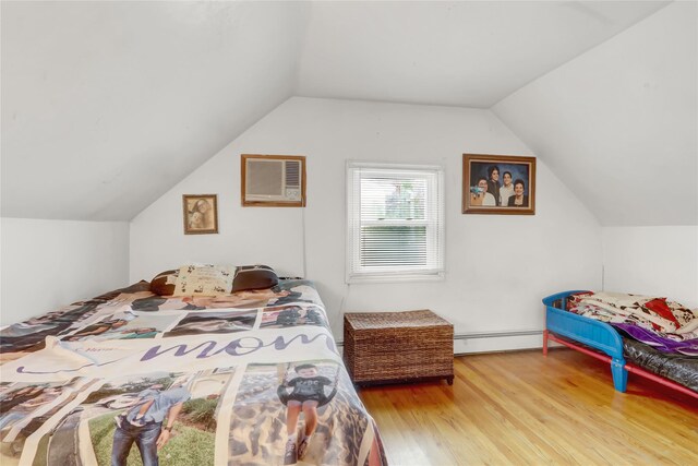 bedroom with a wall unit AC, a baseboard heating unit, wood finished floors, and vaulted ceiling