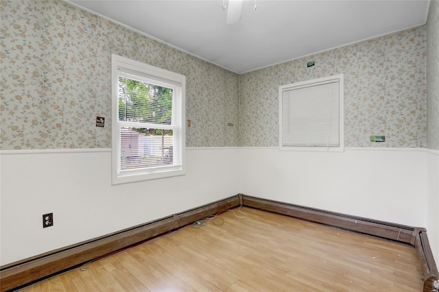 spare room featuring a wainscoted wall, wallpapered walls, a ceiling fan, wood finished floors, and crown molding