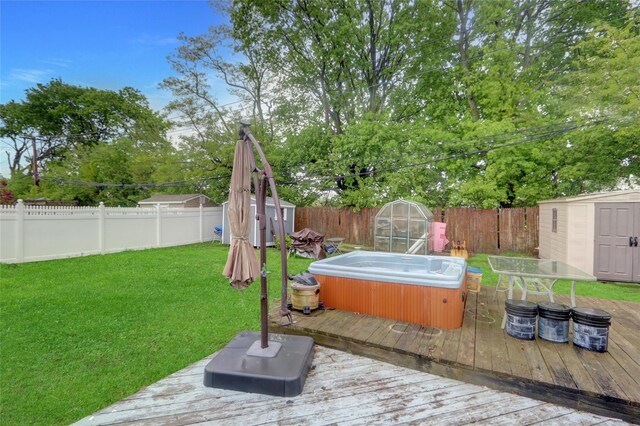 wooden terrace featuring a shed, an outdoor structure, and a hot tub