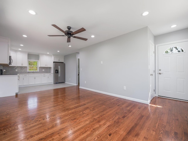 unfurnished living room with ceiling fan, recessed lighting, light wood-style flooring, and a sink