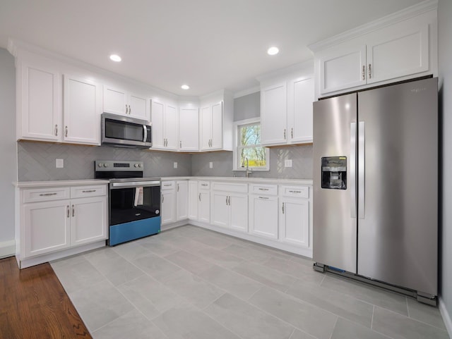 kitchen with white cabinetry, a sink, appliances with stainless steel finishes, light countertops, and backsplash