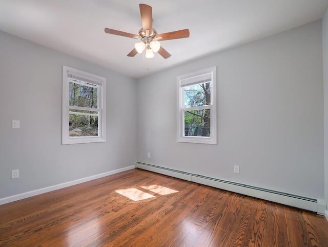 empty room featuring baseboard heating, baseboards, wood finished floors, and a ceiling fan