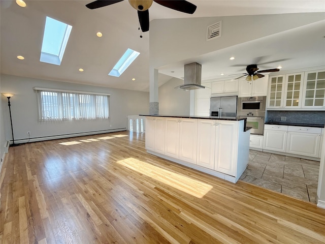 kitchen featuring dark countertops, stainless steel appliances, a ceiling fan, and high vaulted ceiling