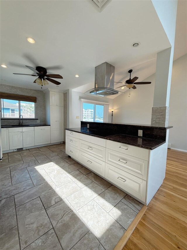 kitchen featuring recessed lighting, island range hood, ceiling fan, a sink, and white cabinetry