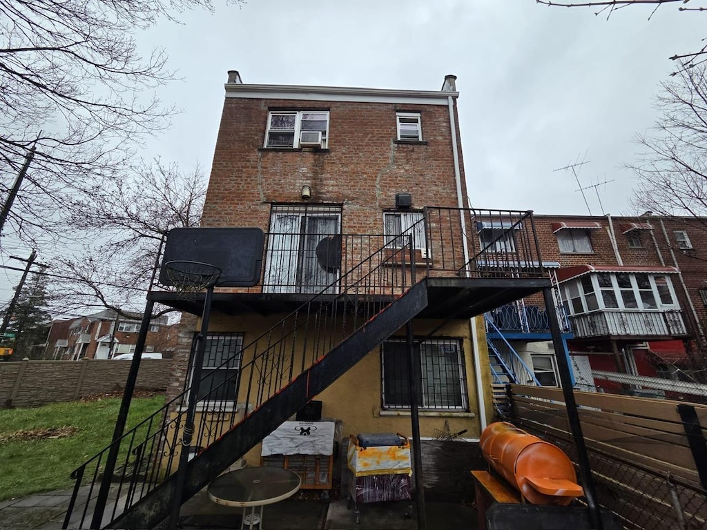 rear view of property featuring fence, stairway, a wooden deck, and brick siding