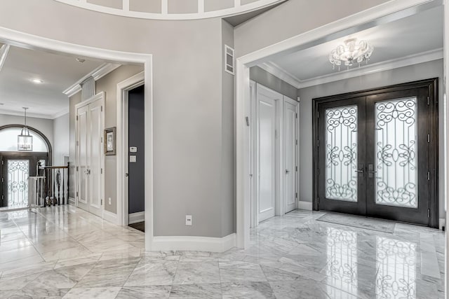 entryway featuring an inviting chandelier, french doors, ornamental molding, and marble finish floor