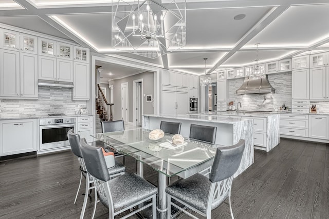 dining area featuring an inviting chandelier, stairway, coffered ceiling, and dark wood finished floors