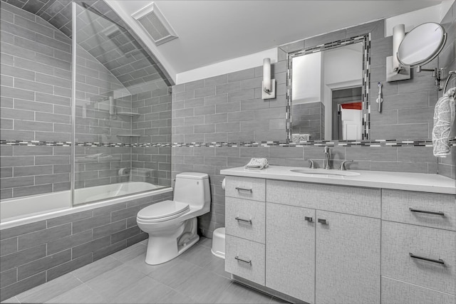 full bathroom featuring visible vents, tiled shower / bath, toilet, tile walls, and vanity