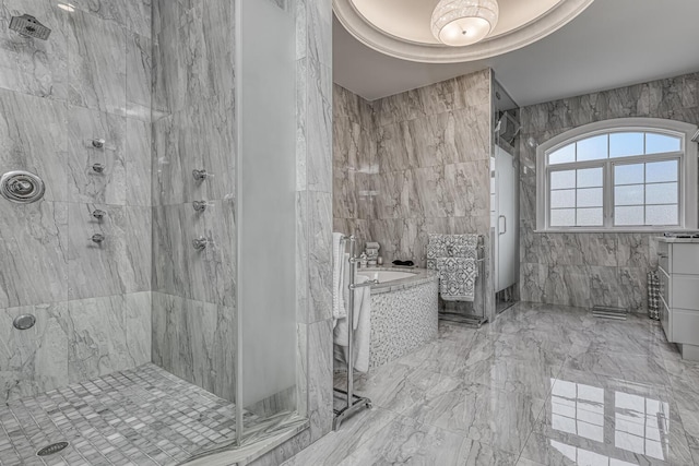 full bathroom featuring a shower stall, a bath, marble finish floor, and tile walls