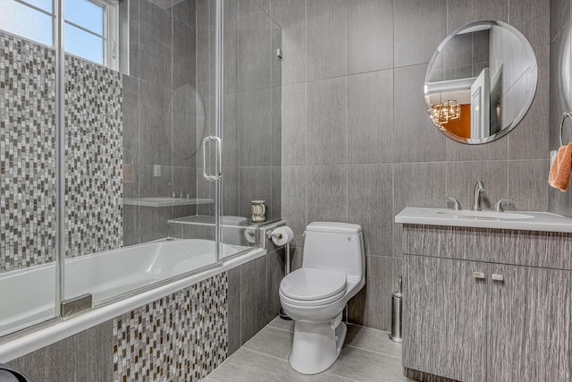 full bath featuring tiled shower / bath combo, tile patterned flooring, tile walls, toilet, and vanity