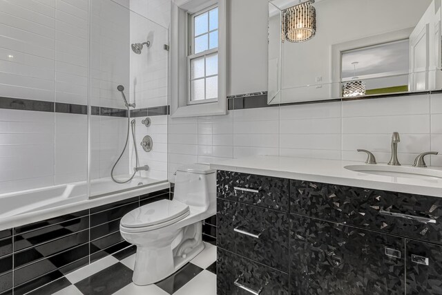 bathroom with tiled shower / bath combo, toilet, tile walls, vanity, and backsplash