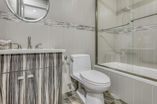 full bathroom featuring toilet, tile walls, and bath / shower combo with glass door